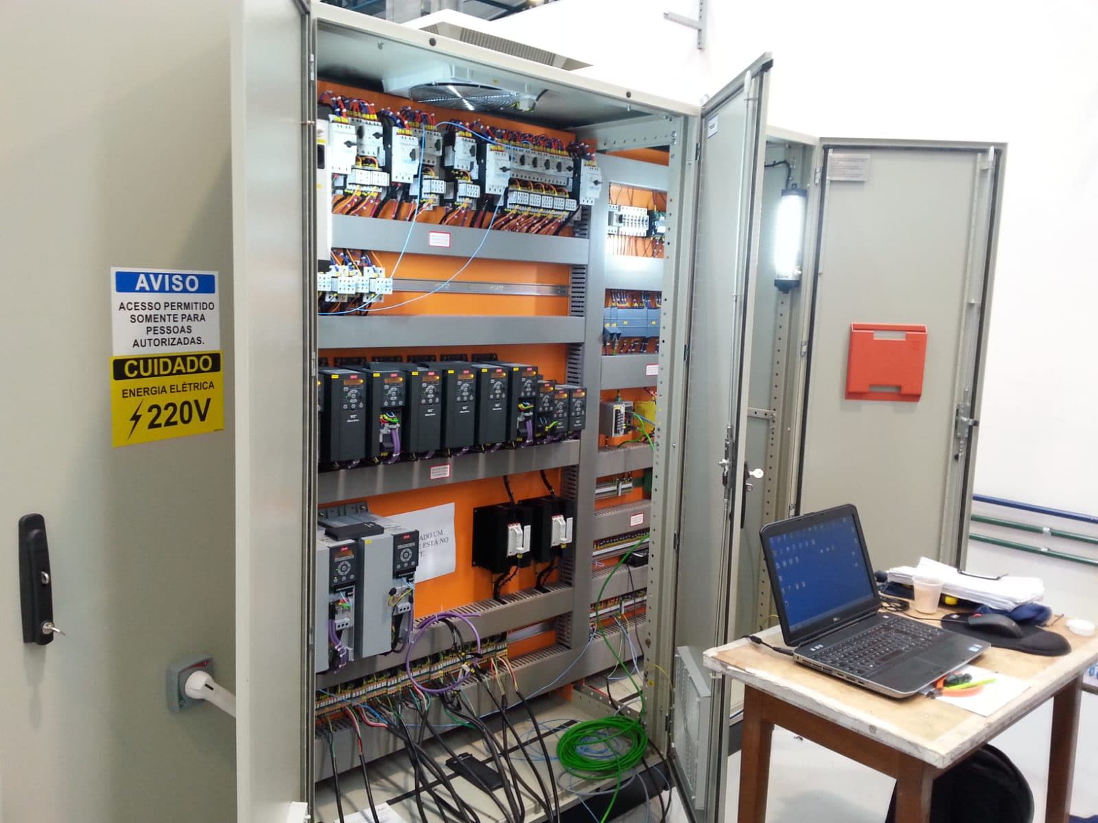 Painel elétrico industrial da Maxtec aberto em comissionamento, com inversores, disjuntores-motor e notebook de testes