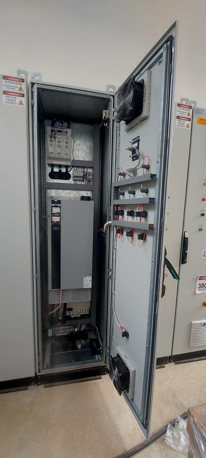 Painel com inversor de frequência de grande porte, de porta aberta, com ventilador na porta e outros painéis ao lado