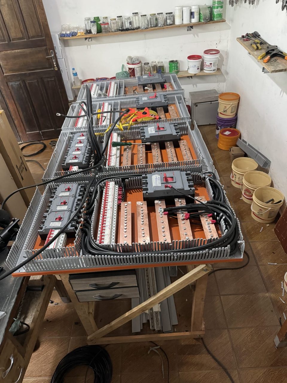 Painéis elétricos industriais em montagem na bancada da oficina da Maxtec, com barramento de cobre e disjuntores